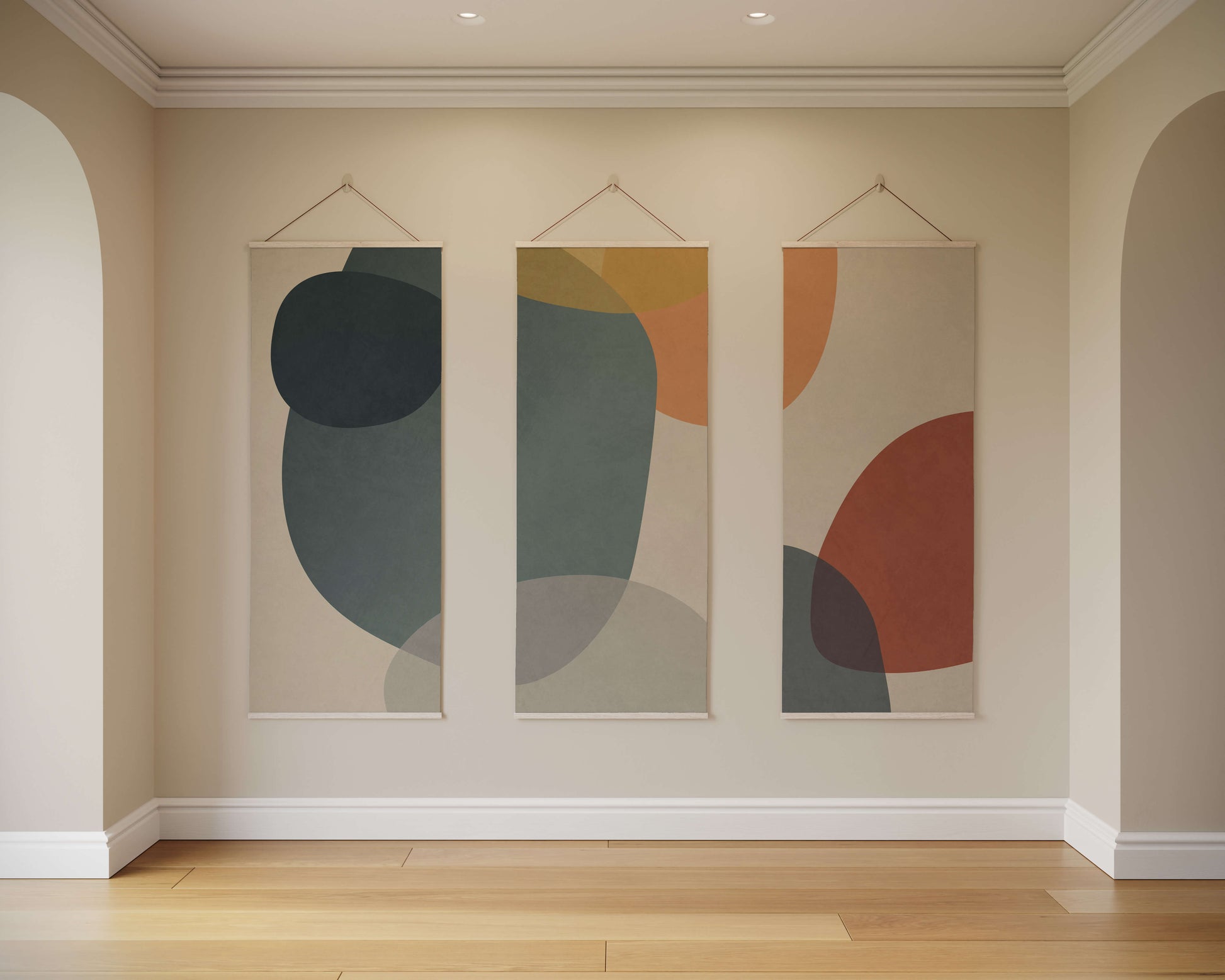 Three abstract wall hangings on a beige wall with wooden flooring.