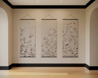 Three floral wall hangings on a beige wall with black trim.