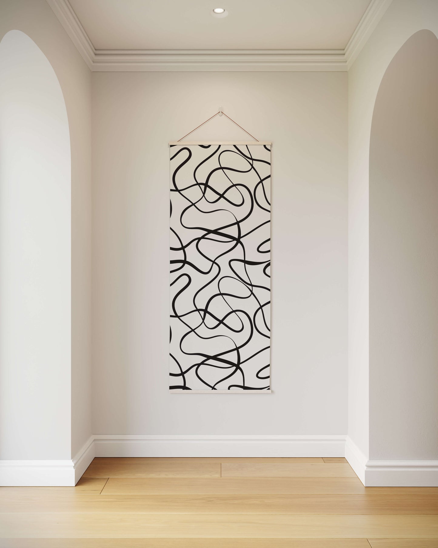 Abstract black and white wall art hanging in a room with white walls and wooden floor.