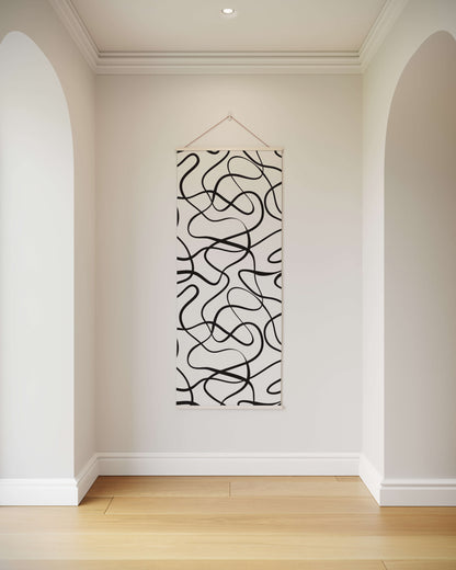 Abstract black and white wall art hanging in a room with white walls and wooden floor.
