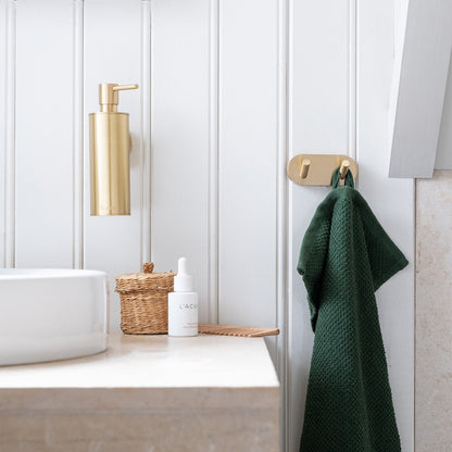 Bathroom with matt brass accessories, green towel, and white sink.