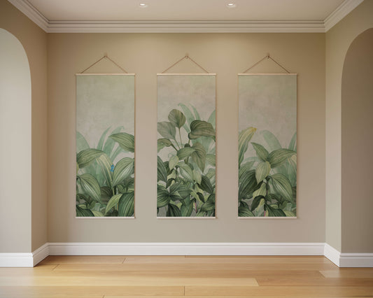 Three vertical wall art pieces with green leaf patterns hanging on a beige wall.