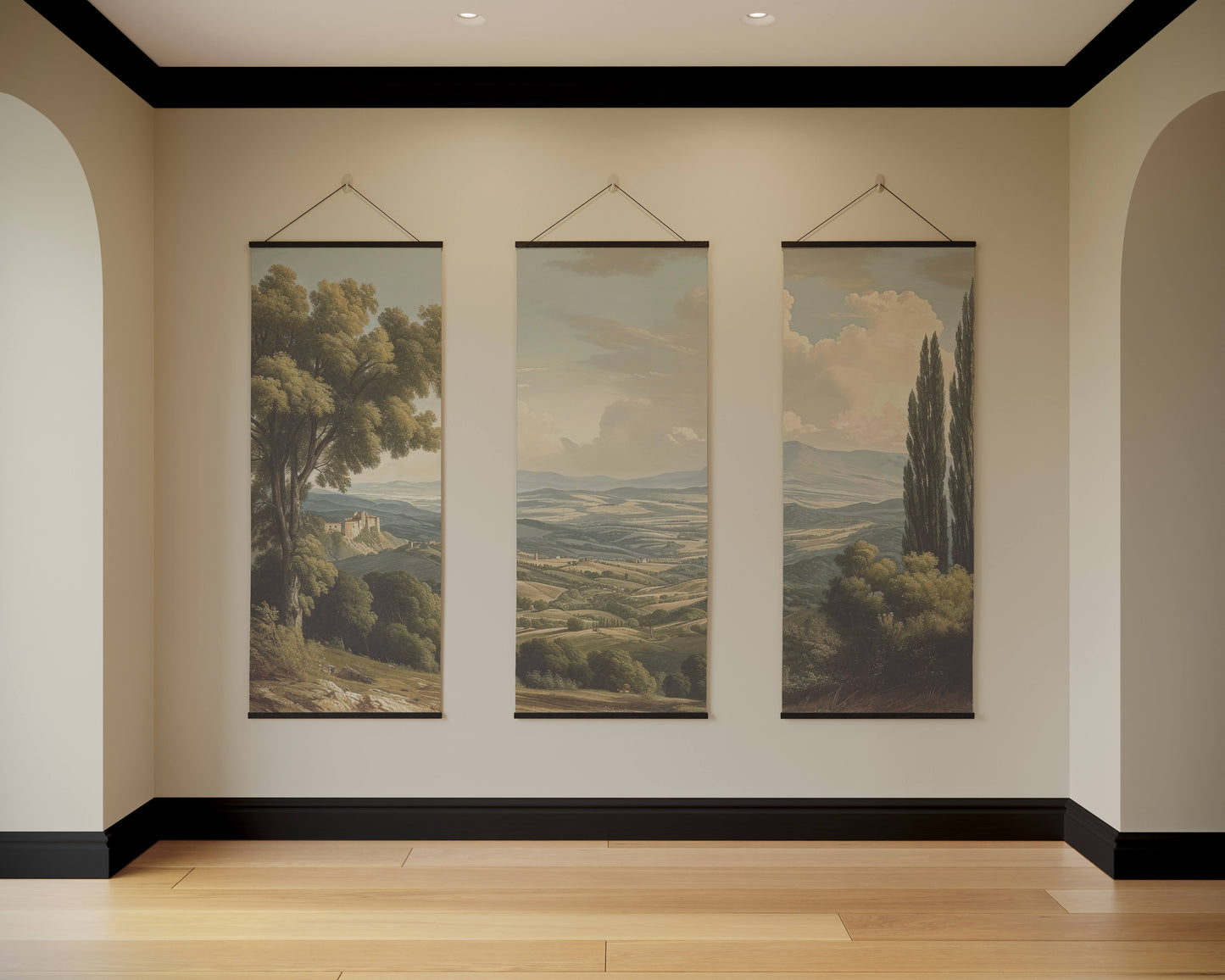 Three landscape paintings hanging on a wall in a room with wooden flooring.
