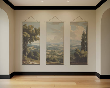 Three landscape paintings hanging on a wall in a room with wooden flooring.