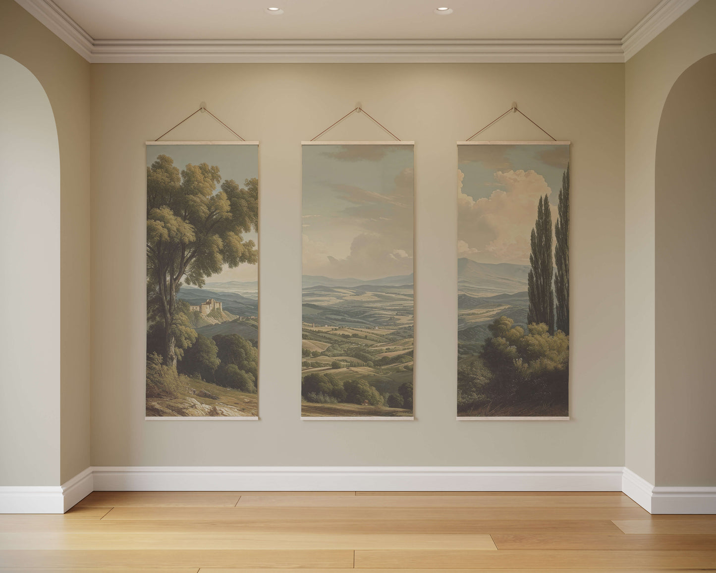 Three landscape paintings hanging on a wall in a room with wooden flooring.
