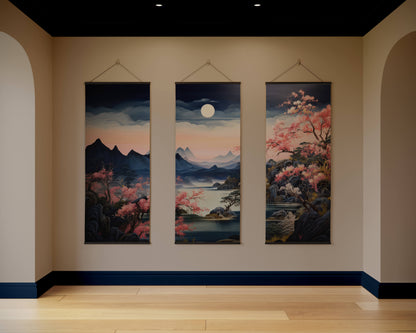 Three hanging artworks depicting a landscape with mountains, cherry blossoms, and a moon on a beige wall.