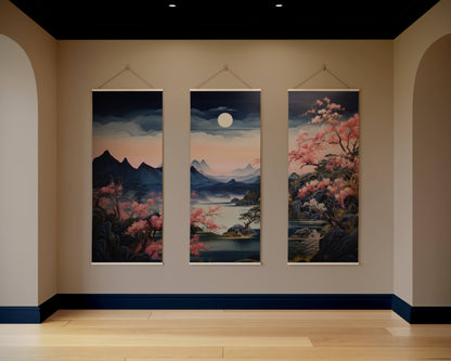 Three hanging artworks depicting landscapes with mountains and cherry blossoms in a room.