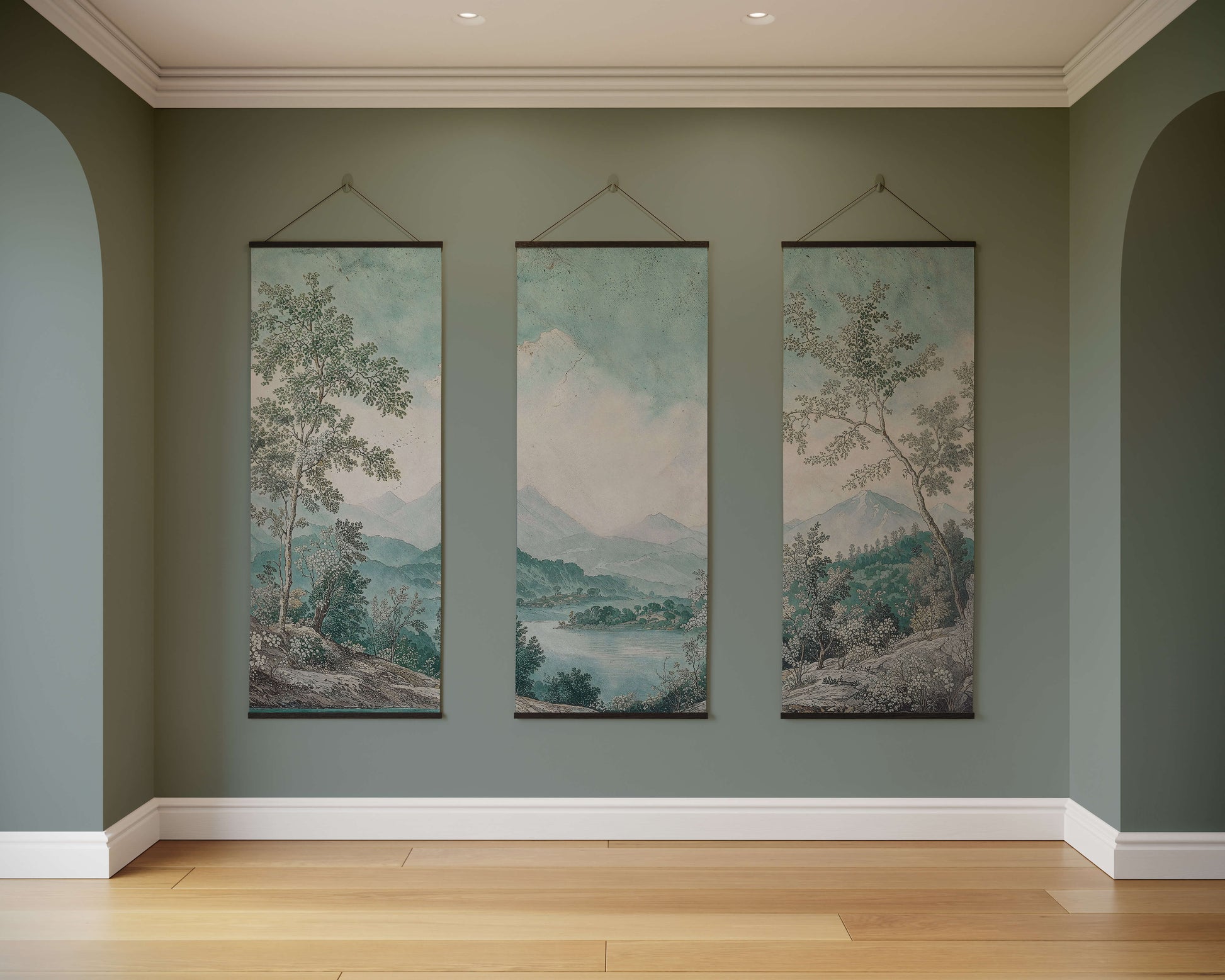 Three landscape paintings hanging on a wall in a room with wooden flooring.