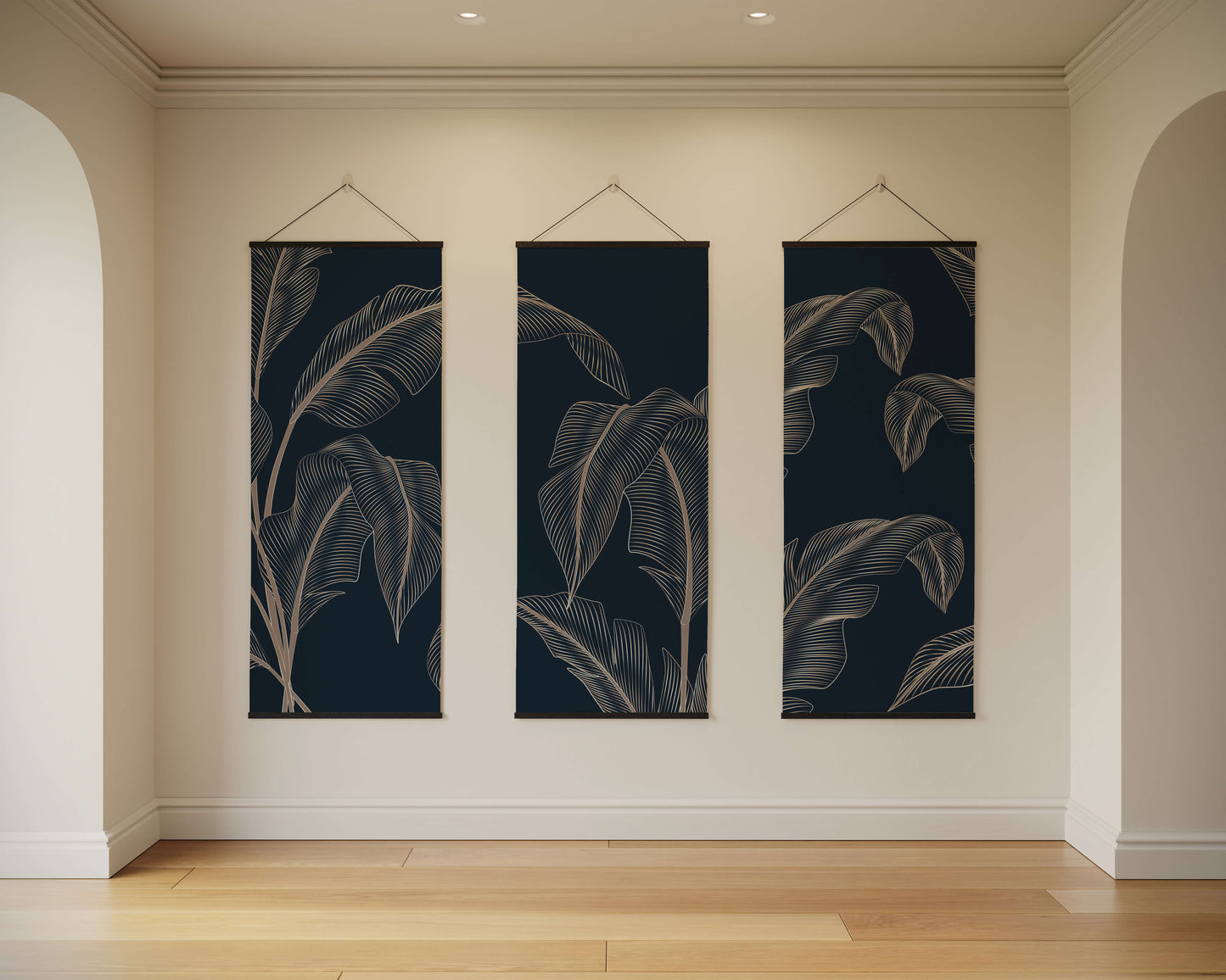 Three vertical wall art pieces with leaf patterns hanging on a beige wall.