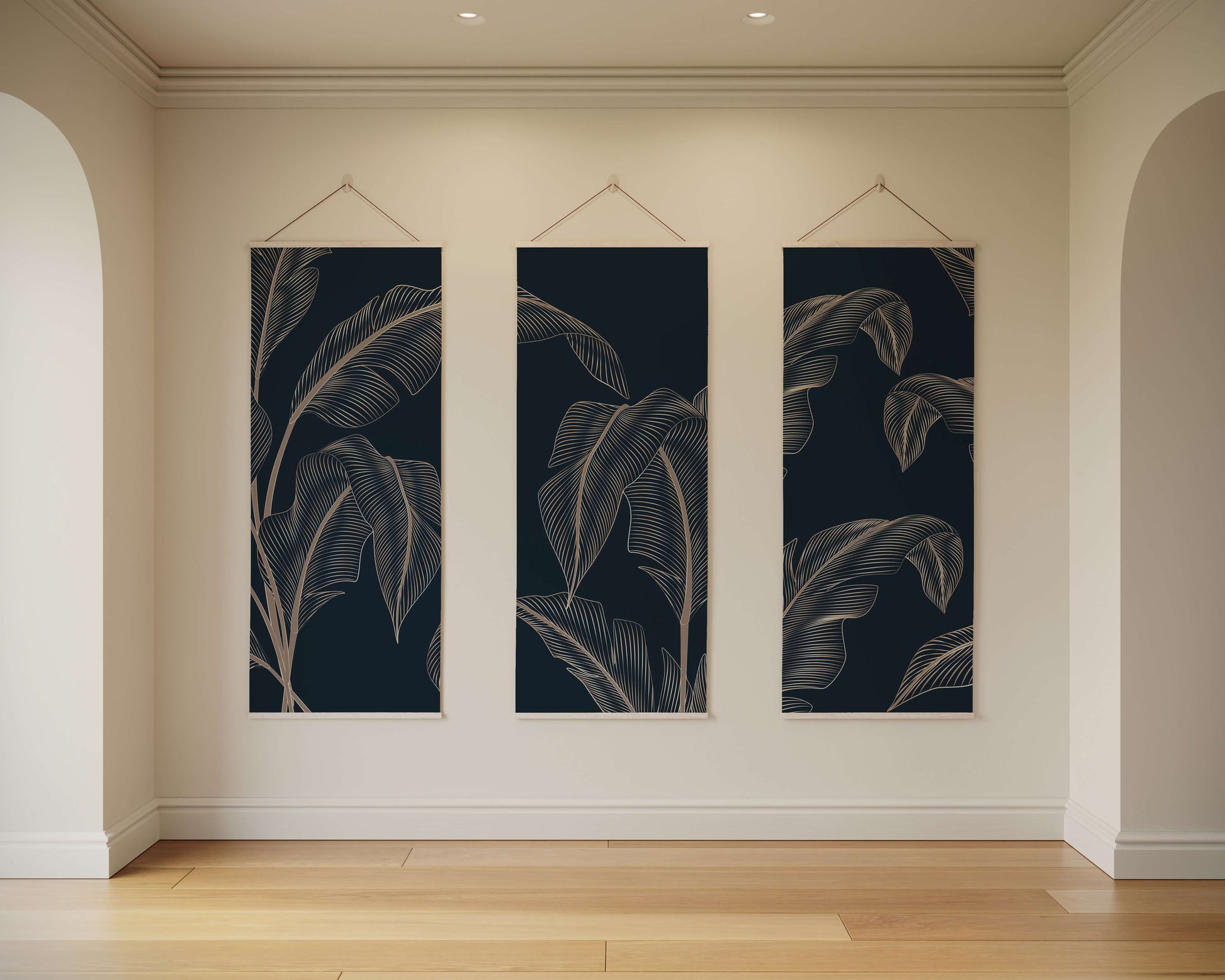 Three vertical wall art pieces with leaf patterns hanging on a beige wall.