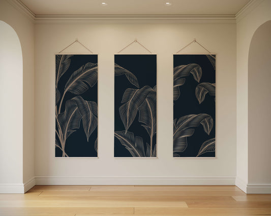 Three vertical wall art pieces with leaf patterns hanging on a beige wall.
