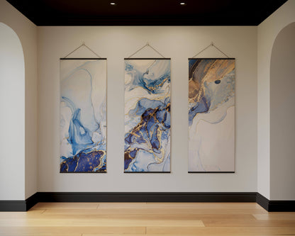 Three abstract paintings hanging on a wall in a room with wooden flooring.