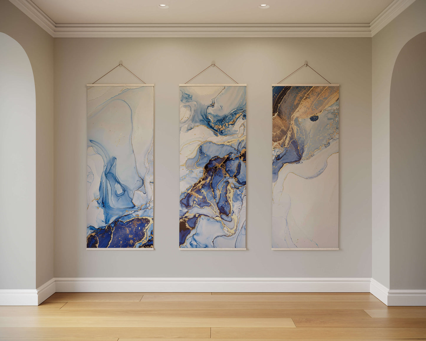 Three abstract paintings hanging on a wall in a room with wooden flooring.