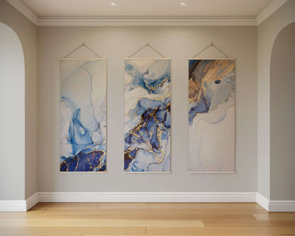Three abstract paintings hanging on a wall in a room with wooden flooring.