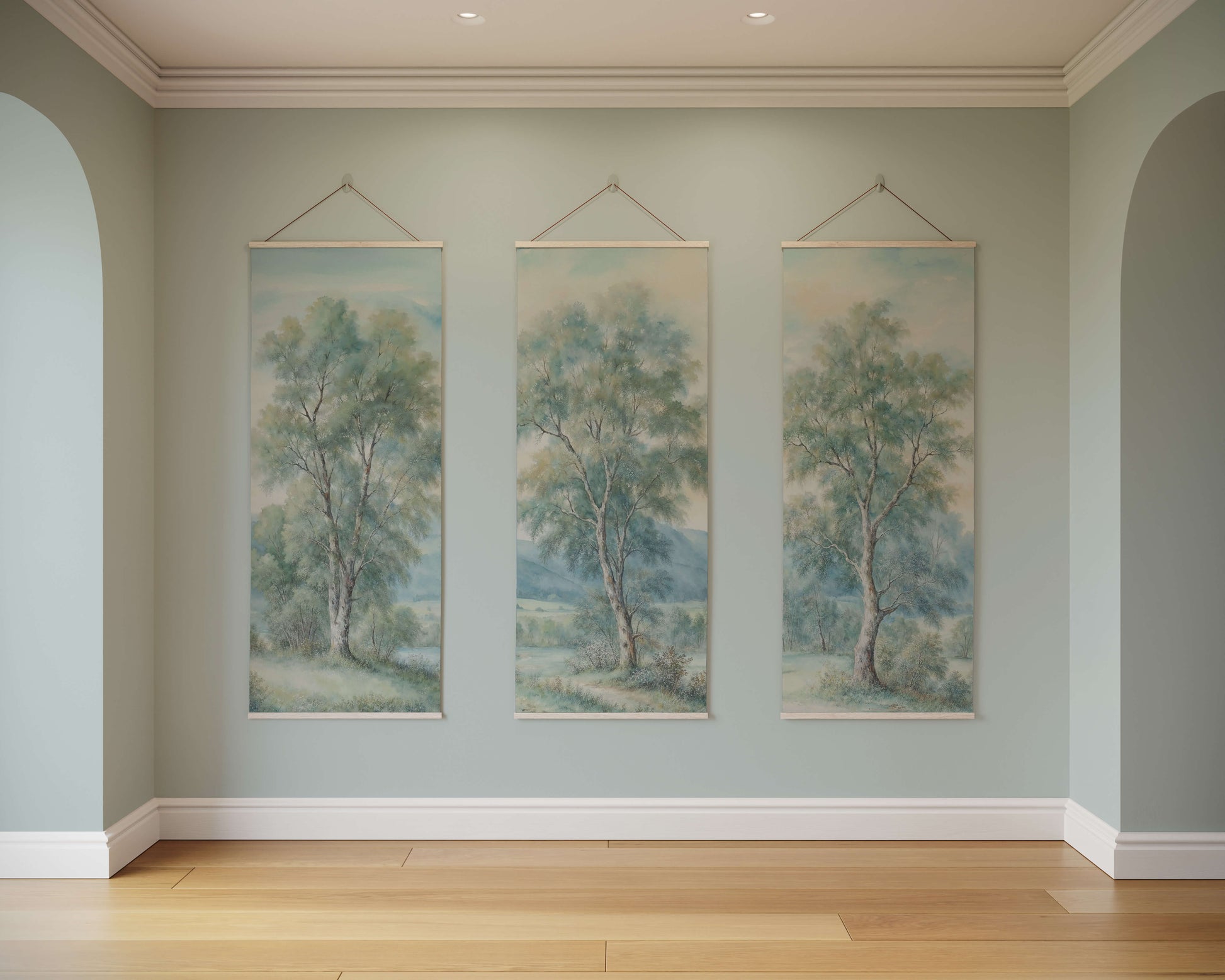 Three tree paintings hanging on a wall in a room with wooden flooring.