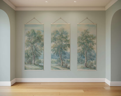 Three tree paintings hanging on a wall in a room with wooden flooring.