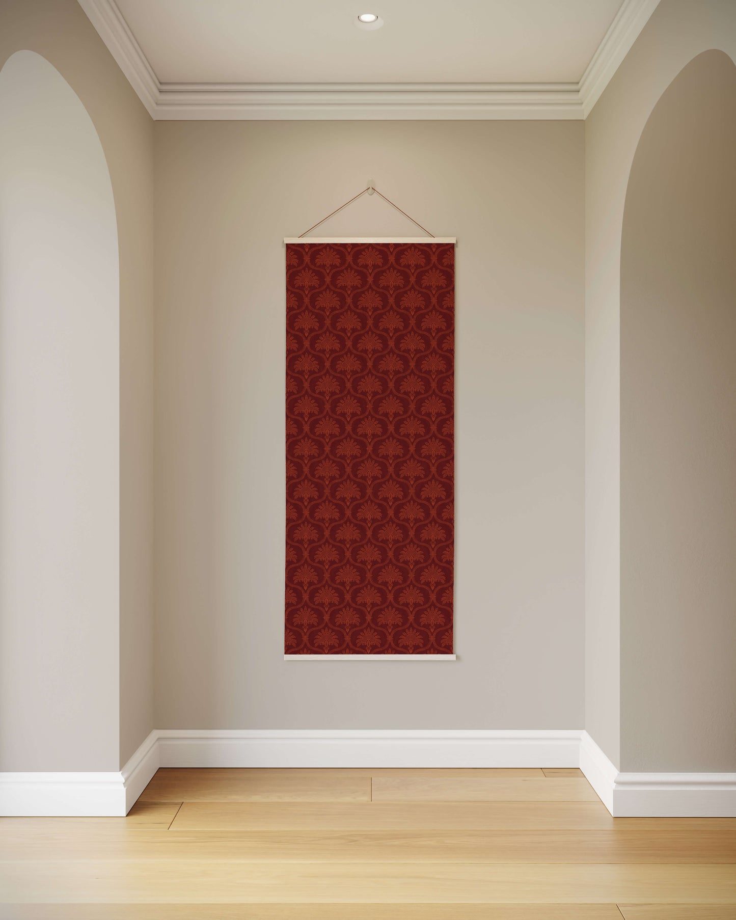Red patterned wall hanging on a beige wall in a room with wooden flooring.