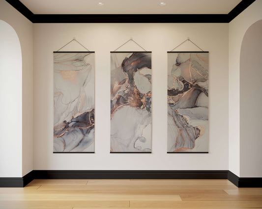 Three abstract wall hangings on a white wall with a wooden floor.