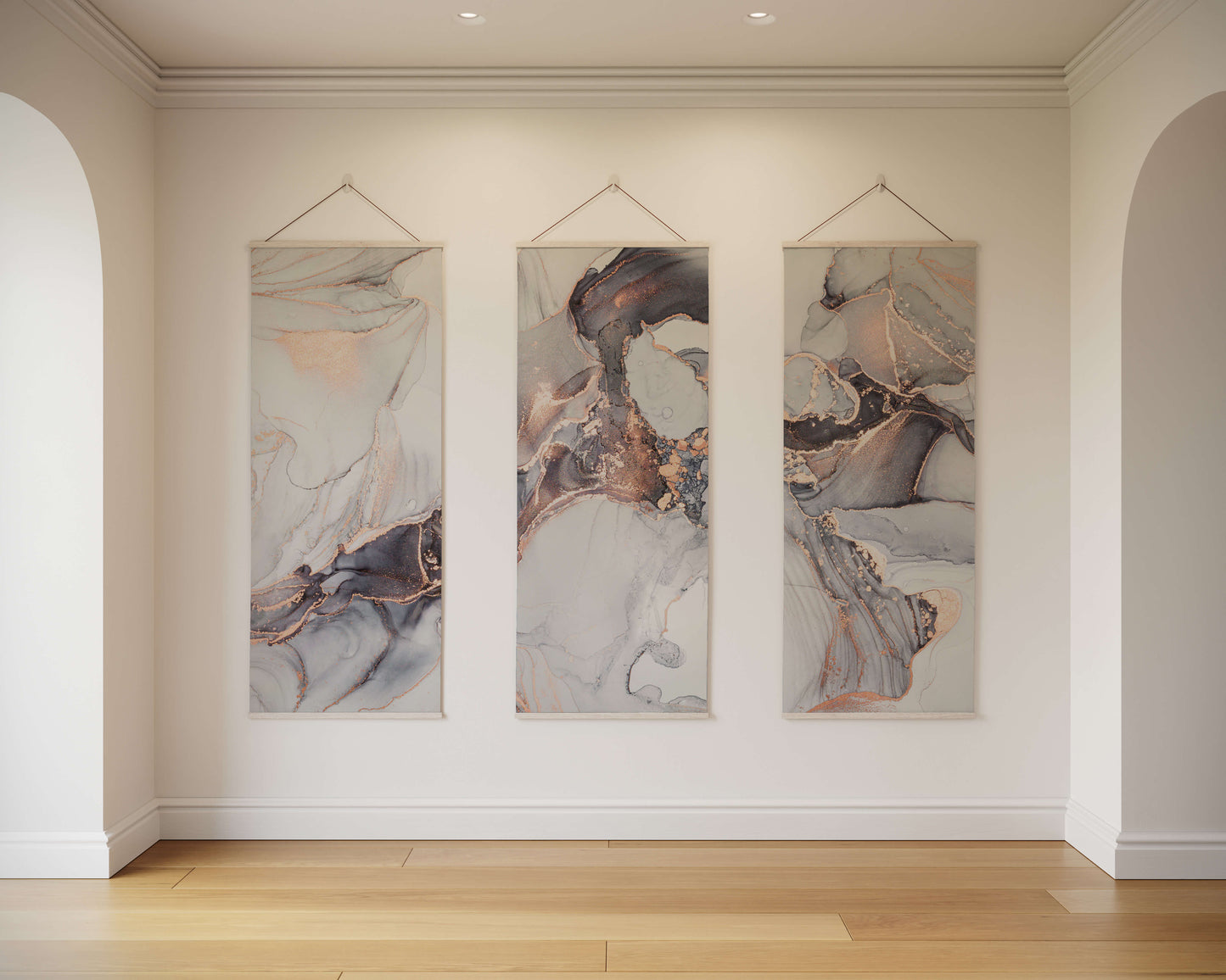 Three abstract artworks hanging on a wall in a room with wooden flooring.