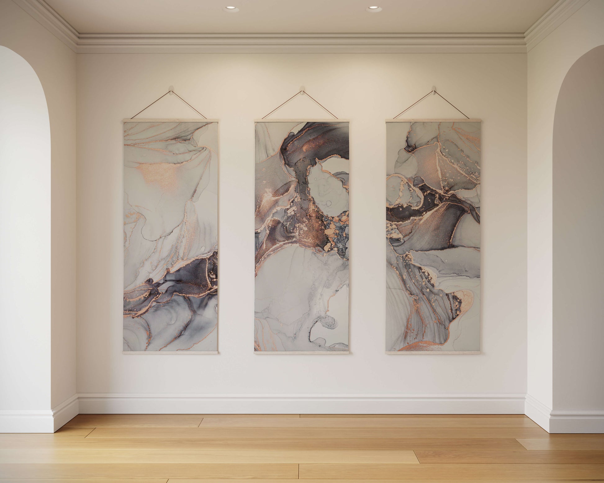 Three abstract artworks hanging on a wall in a room with wooden flooring.